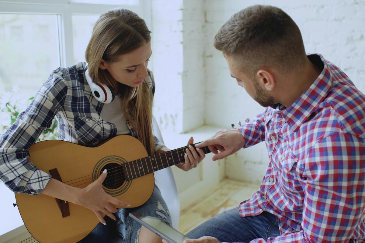 Un professeur de guitare montre un accord à son élève